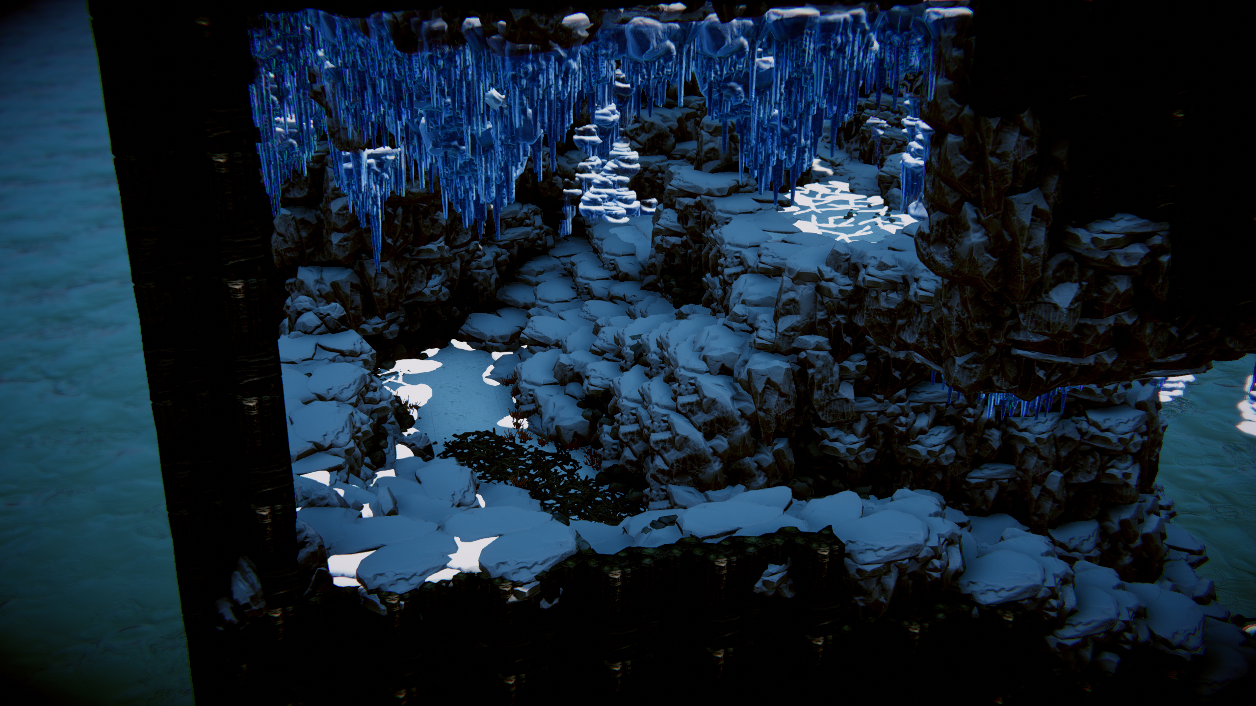 Snow-covered rocks beneath blue icicles in an expansive ice cave